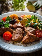 Fried pork loin nuggets with cooked vegetables on wooden table
