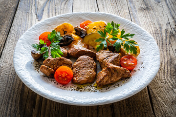 Fried pork loin nuggets with cooked vegetables on wooden table
