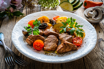 Fried pork loin nuggets with cooked vegetables on wooden table
