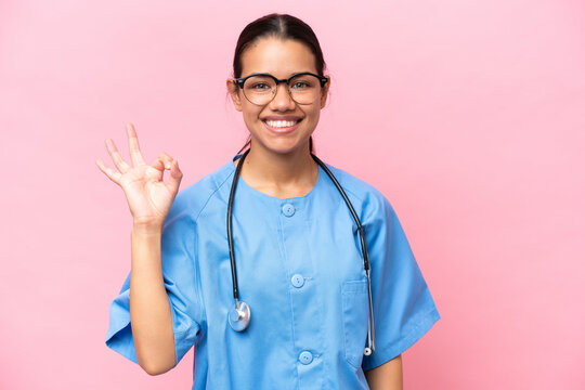 Young nurse Colombian woman isolated on pink background showing ok sign with fingers