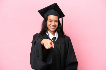 Young university Colombian woman graduate isolated on pink background points finger at you with a confident expression