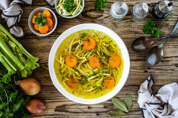 Broth - chicken soup with vegetables on wooden table
