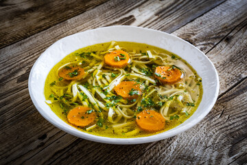 Broth - chicken soup with vegetables on wooden table
