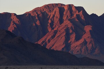 Die Berge des Naukluft Gebirge leuchten rot im Licht der untergehenden Sonne. 
