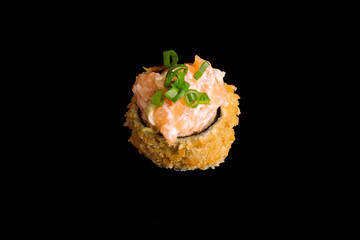 brazilian japanese food isolated on black background sushi breaded with salmon and chives.