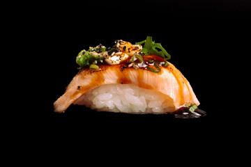 brazilian japanese food isolated on black background nigiri of rice and toasted salmon.