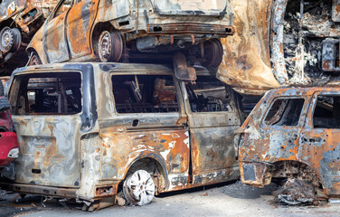 Rusty burnt cars destroyed by rocket explosions. War in Ukraine. Destroyed vehicles of civilians...