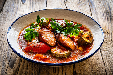 Delicious letcho - vegetables with sausages on wooden table
