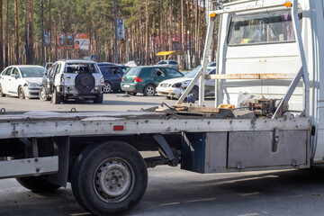 Lots of old cars ready for recycling. Car removal by tow truck. The car is getting ready to be loaded onto a tow truck. Old wrecked cars in a junkyard are waiting to be destroyed in a recycling park. - obrazy, fototapety, plakaty