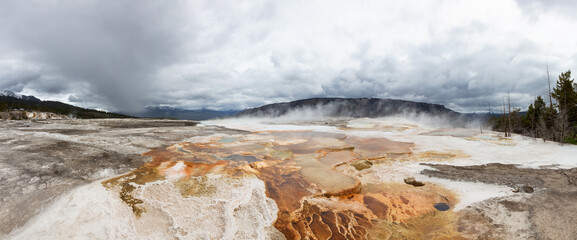 Hot spring Geyser with colorful water in American Landscape. Cloudy Sky. Yellowstone National Park, Wyoming, United States. Nature Background Panorama