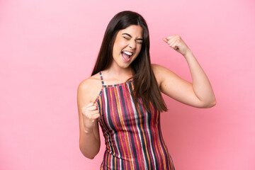 Young Brazilian woman isolated on pink background celebrating a victory