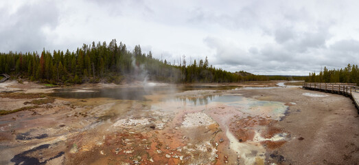 Hot spring Geyser with colorful water in American Landscape. Cloudy Sky. Yellowstone National Park, Wyoming, United States. Nature Background Panorama