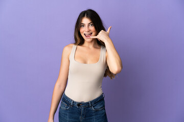 Young caucasian woman isolated on purple background making phone gesture. Call me back sign