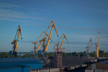 Fototapeta na wymiar Cranes in an industrial zone in port against the sky by summer day