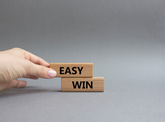 Easy win symbol. Wooden blocks with words Easy win. Beautiful grey background. Businessman hand. Business and Easy win concept. Copy space.