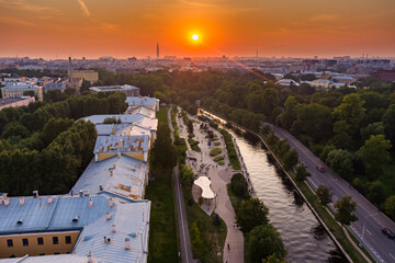 Aerial view of the public park of the Karpovka River Embankment in St. Petersburg at sunset, Russia, recreation areas, benches and amphitheater, botanical garden opposite the park