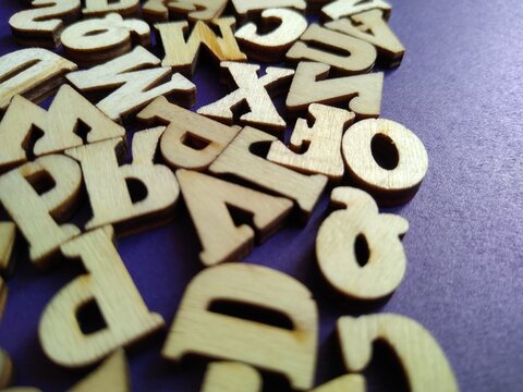 wooden letters of the alphabet scattered on a purple background with space for text
