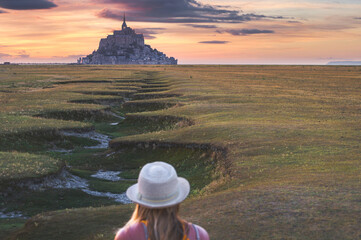 Young girl enjoying the View of the Castle on St Michael's Mount during beautiful sunset, Mont Saint Michael, France