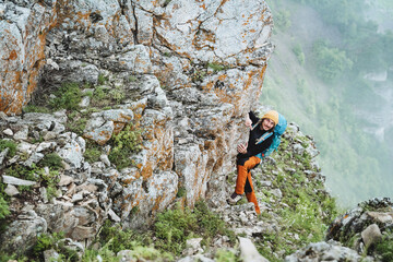A guy climbs into the mountains to the top, a man is engaged in mountaineering, the smile of a man in the mountains, a steep rock.