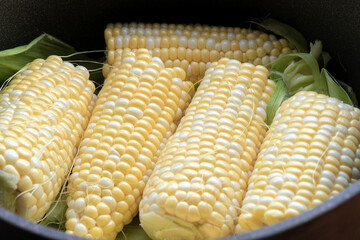 Raw cobs of young corn with leaves on a wooden table. the inscription on the cob 
