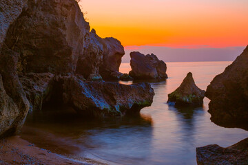 Rocky seascape with bizarre rocks and long exposure at sunset