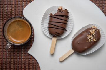 Ice cream covered with chocolate and some nuts with a cup of coffee