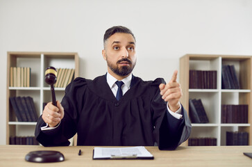 Portrait of stern judge knocking on judge's gavel passes sentence and declares case closed. Man in...