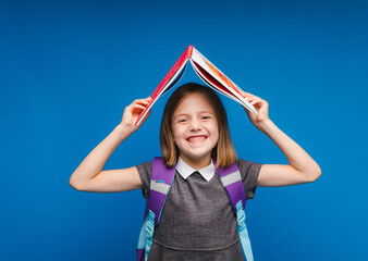 A book roof over your head. A little girl holds a textbook on her head. A little girl with a book...