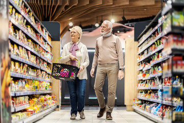 A senior couple purchases groceries at supermarket.