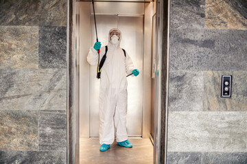 Coronavirus alert. A man in protective clothing prevents the spread of the infection in a hotel elevator. Stay healthy, COVID19 outbreak situation