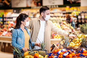 A happy couple purchasing fresh vegetables at supermarket during covid 19.