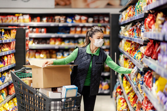 A supermarket employee arranges groceries on shelves during corona virus.