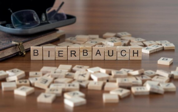 bierbauch Wort oder Konzept dargestellt durch hölzerne Buchstabenfliesen auf einem Holztisch mit Brille und einem Buch