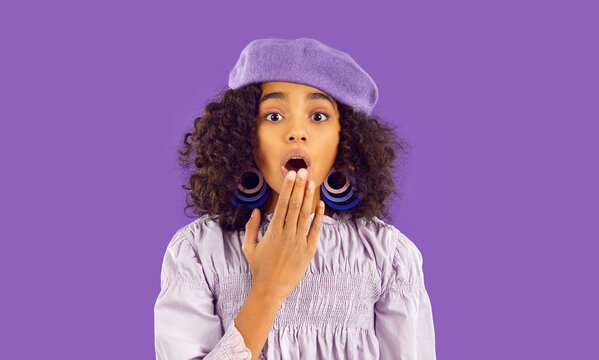 Portrait of stunned teen African American girl isolated on purple studio background feel shocked by unexpected news. Amazed teenage biracial shocked by amazing sale deal or promotion.