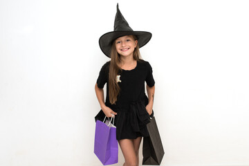 Discounts,seasonal sales. Fashion. a girl with long dark hair in a witch hat and bags in her hands.  Happy Halloween. The concept of celebrating the autumn holiday.