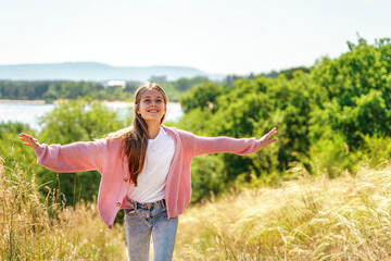 A relaxed girl runs through the fields with her hands raised to the sky in summer. The concept of travel, dreams and freedom.