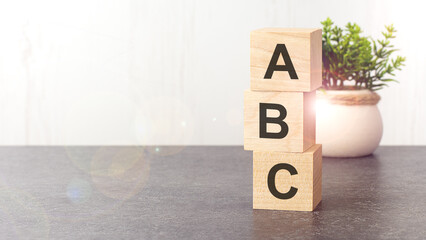 letters of the alphabet of ABC on wooden cubes, green plant, white background