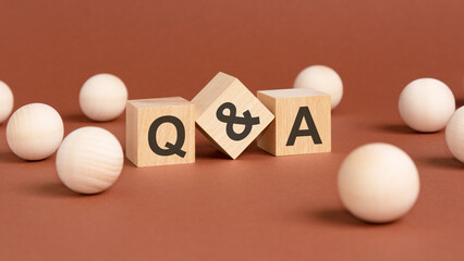 wooden cubes with letters Q and A on brown background. front view