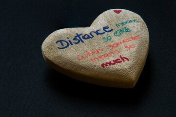 Heart shaped stone with a quote about long distance relationship on it on a black background