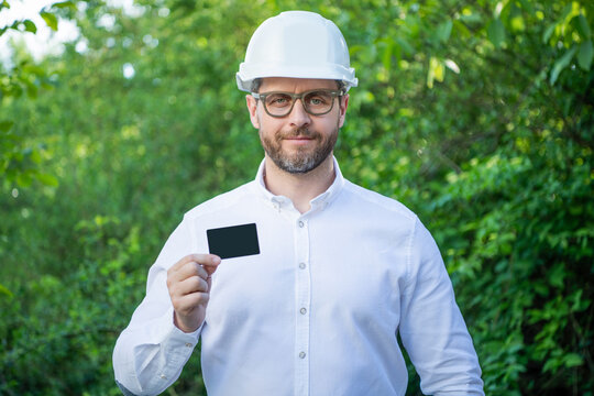 Man Taskmaster In Hardhat Showing Blank Contact Card Outdoors, Copy Space