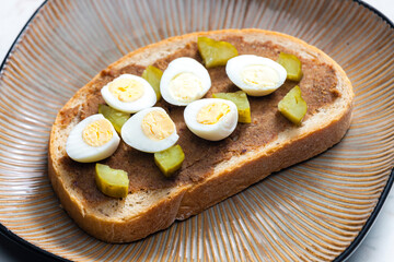 cracklings spread with pickled cucumber and boiled egg on slice of bread