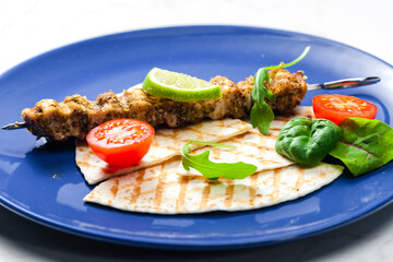 herbal meat skewer  with pita bread, tomatoes and lime