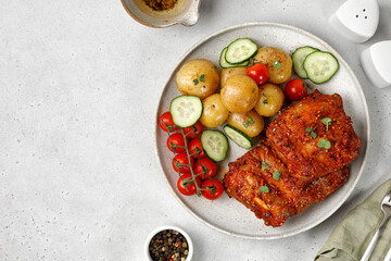 Dish, plate with Marinated pork bbq ribs, young potatoes, tomatoes on ceramic plate and grey background. Hearty Dinner, lunch, meal.
