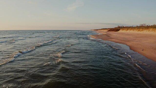 Sandy beach washed by foamy sea waves, drone video. No people.