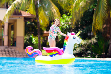 Child on unicorn float in swimming pool. Kids swim