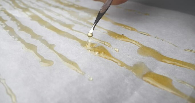 golden dabs of cannabis extract resin and smoking scraper parchment paper. High quality 4k footage