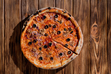 Pizza with tuna, olives, onions, mozzarella cheese and tomato sauce on wood background. Top view, copy space