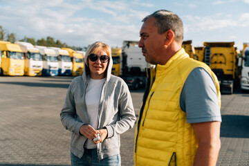 Mature woman and man at cargo warehouse, truck drivers delivery partners.