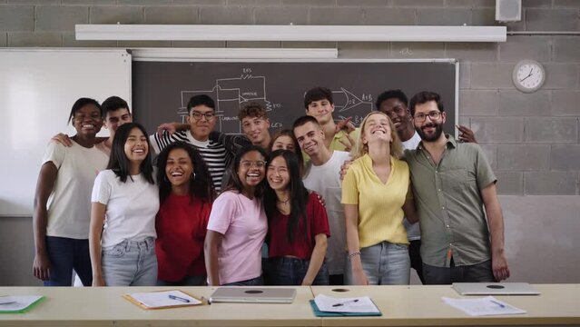 Portrait of a group of students hugging each other in class looking at the camera. Young people of different ethnicities posing for a photo in the classroom. Back to school.
