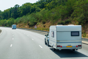 Motorhomes driving along a lonely highway lined with trees.